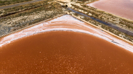 Aerial closeup of the tanks of a large salt mine. The water in the salt pan is red.