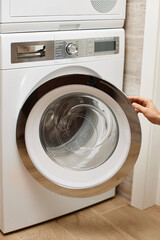 female hand open or close the door in washing machine at home