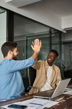 Happy diverse young business men colleagues work team partners giving high five as concept of friendly help, corporate goal achievement, project market growth, trust and support in teamwork. Vertical