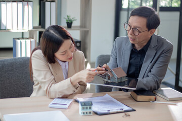 Fototapeta premium A real estate business woman and man sign a house contract and explain their housing project.