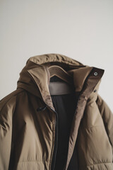 Mocha Mousse displayed in a stylish winter coat hanging on a wall with neutral background