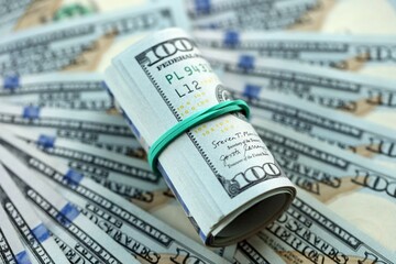 Roll of hundred dollar bills USD banknotes lies on big amount of united states money