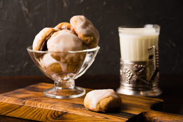 Delicious homemade gingerbread cookies with honey, cinnamon and vanilla in a glass bowl and a glass of hot milk on a dark background
