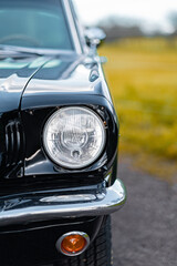 Close-Up View of a Classic Black Car Headlight in Outdoor Setting