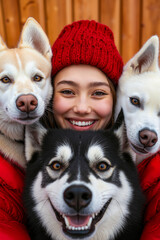 Fototapeta premium A woman in a red hat and red jacket with three husky dogs