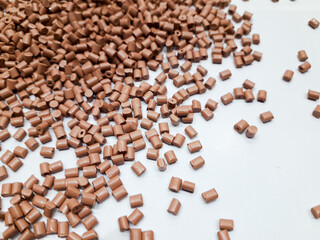 Milk chocolate color masterbatch granules on white background, color pigment carrier polymer in plastic industry. Suitable for plastic company catalog design