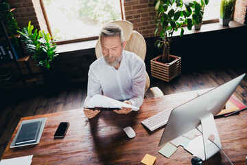 Photo of successful nice man specialist dressed shirt reading document report contract indoors...