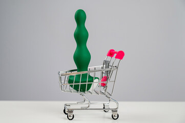Green anal plug in miniature shopping cart. 