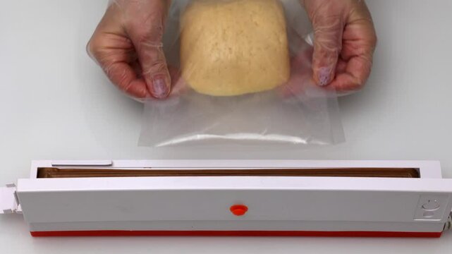 This close-up vedeo features a woman wearing gloves as she efficiently packs cheese using a vacuum packer, emphasizing food safety and preservation techniques.