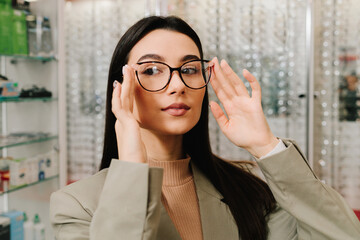 Woman is holding a cat eye eyeglasses frame in the optics. Eyeglasses with clear lens for eyesight...