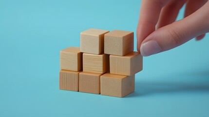 Obraz premium Hand placing wooden blocks building a structure