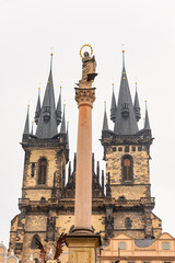 Towers of the stunning Tyn church on white background of foggy sky in Prague.