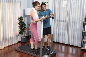 Fototapeta premium Athletic and sporty young couple or fitness buddy running on running machine together, home body workout exercise session as healthy sport lifestyle at home. Gaiety home exercise workout training.
