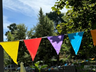 Colorful pennant Summer party string decoration against a tree and the summer sky