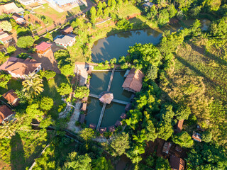 Serene Pond in Lush Landscape:  An aerial view captures a tranquil pond nestled amidst a vibrant landscape, showcasing a tapestry of lush greenery and quaint structures.
