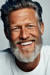 Fototapeta premium A man with a beard and white shirt is smiling and looking at the camera. Concept of happiness and warmth, as the man's smile