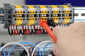 Measurement of electrical parameters in a switchboard using a multimeter.
