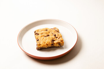 Chocolate Chip Cookie Bar on White Plate with Red Rim on white background