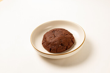 a big chocolate cookie on a plate with solid background