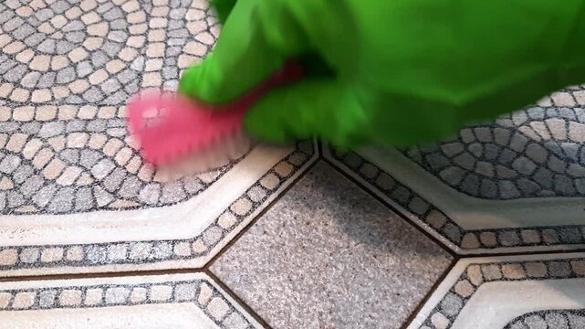 Woman washes floor with small brush. Cleaner hand in household glove close-up against background of tiles during cleaning. spring cleaning checklist