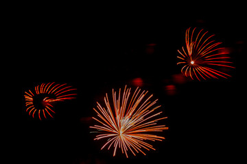Fototapeta premium Red-orange sparks of fireworks on the black sky. .