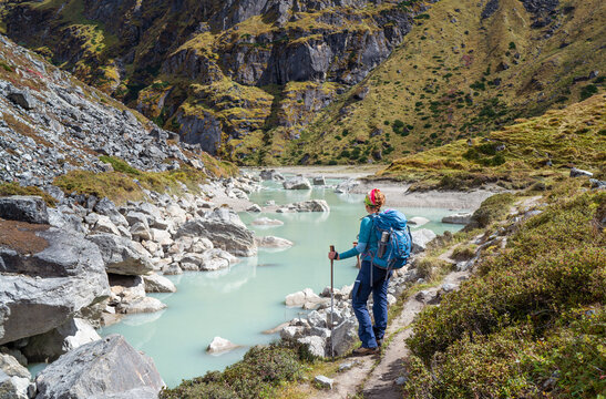 Female trekker dressed active style with backpack enjoying glacier river on Mera peak climbing route near high altitude Sabai Tso glacial lake cca 4350m. Makalu Barun National Park, , Nepal.