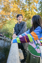 A young Chinese couple in their 20s looks at the pond from a bridge in Luxun Park in Hongkou District, Shanghai, People's Republic of China during the cold season in December 2024.