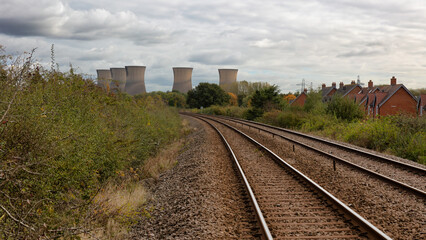 Obraz premium a railway track leads the viewer to five cooling towers at a power station in the distance. Located in Willington, Derbyshire