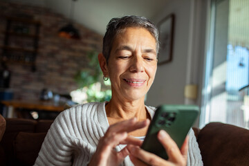 Senior woman relaxing on the couch with smartphone at home