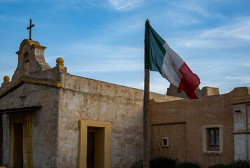 Rustic Charm: A Weathered Church with the Mexican Flag Waving Proudly