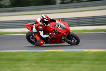 Rider on a red sport motorcycle riding fast through a corner 