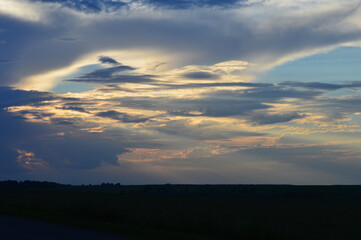 Fototapeta premium Majestic cloud formations at dusk over a tranquil field in rural landscape