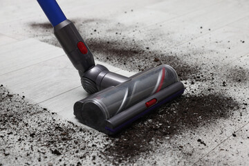Cleaning floor with cordless vacuum cleaner indoors, closeup