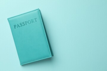 Passport in bright cover on light blue background, top view. Space for text