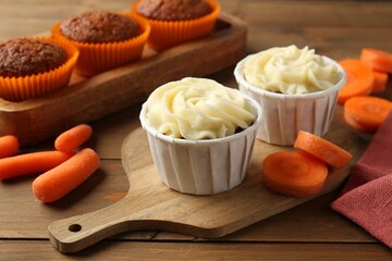 Tasty carrot muffins with fresh vegetables on wooden table, closeup