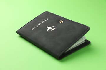 Passport in black cover on green background, closeup