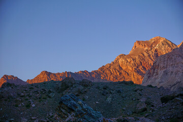 Fototapeta premium Sunset in the mountains. The setting sun highlights the mountain peaks with orange light