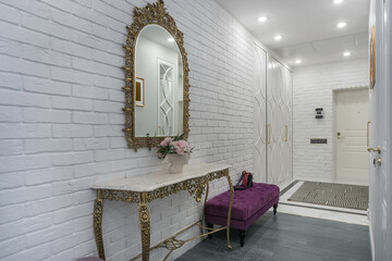 Entrance hall in a private house with white brick walls. The frame of the mirror and the .legs of...