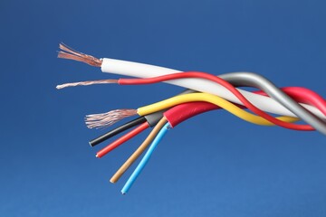 Many stripped electrical wires on blue background, closeup