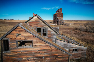 A dilapidated old house sits in a field with a large