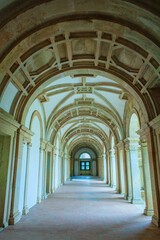 arched corridor with a tiled floor and sunlight streaming through the windows, creating a sense of mystery and intrigue within the historic building.