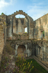 Fototapeta premium ruined interior space with crumbling walls, arched windows, and a patch of vibrant green grass growing within, evoking a sense of history and decay.