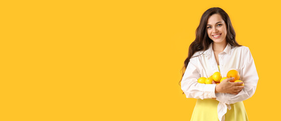 Pretty young woman holding many lemons on yellow background