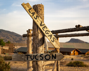 Weathered Wooden Signpost in Desert Landscape: Directions to Las Vegas and Tucson Amidst Arid Vegetation and Blue Sky, Capturing the Spirit of Adventure and Exploration