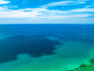 Obraz premium Aerial view of blue sea surface water texture background,Amazing sun reflections Aerial flying drone view Waves water surface texture on sunny tropical ocean