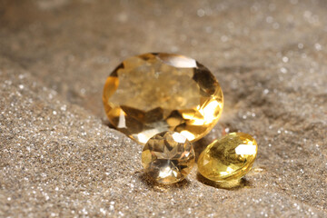 Beautiful shiny gemstones on sand, closeup view
