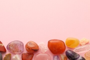 Beautiful natural gemstones on light pink background, flat lay. Space for text
