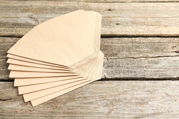 Many paper coffee filters on wooden table, space for text
