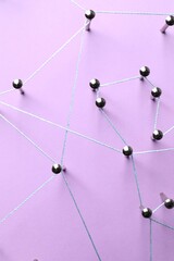Network connection. Nails linked together by thread on violet background, flat lay