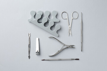 Set of pedicure tools on light grey background, flat lay